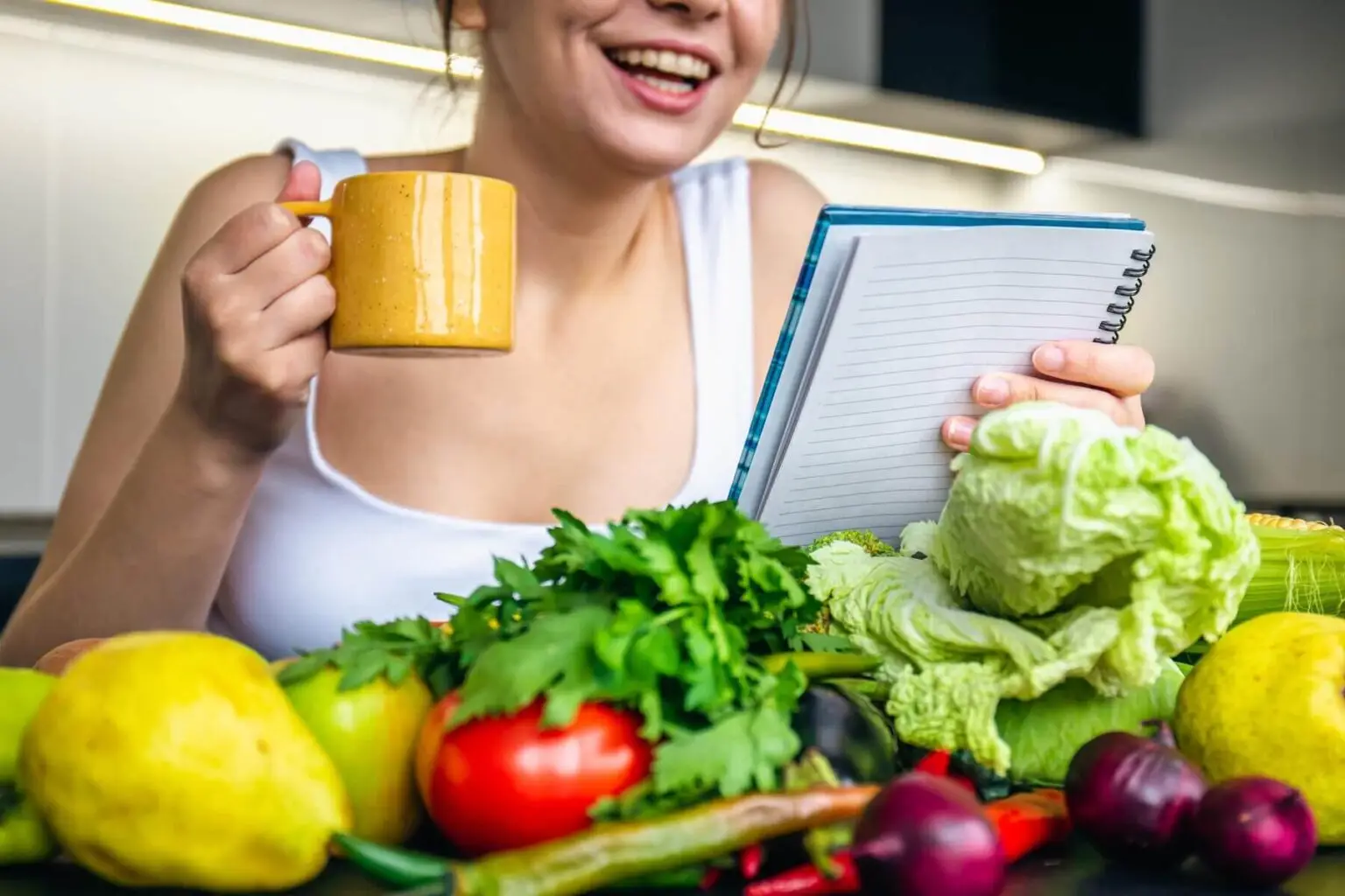 young-woman-kitchen-with-notebook-among-vegetables